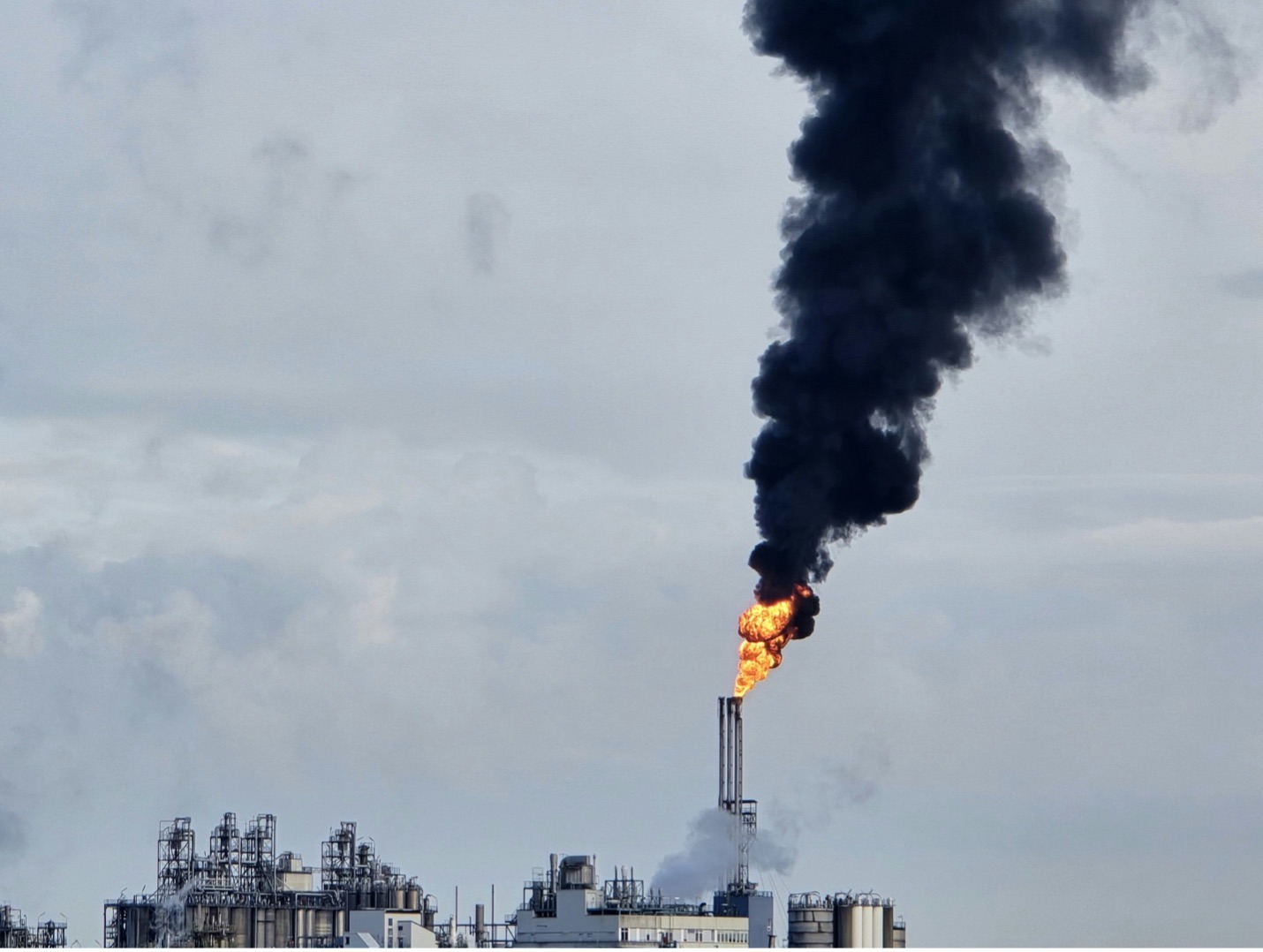 A Large Plume of Black Smoke Rises From a Factory, Indicating Possible Pollution or a Fire Incident.